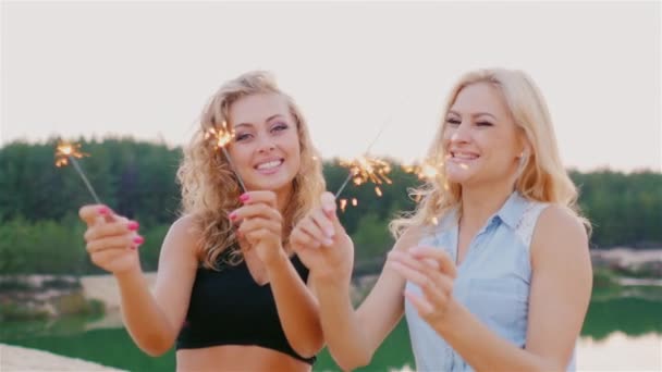 Twee aantrekkelijke vrouw met wonderkaarsen. Lachen op het strand — Stockvideo