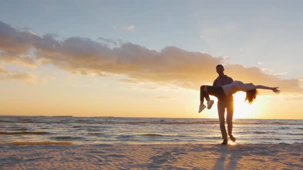 Ein junger verliebter Mann an den Händen seiner Braut. am Strand bei Sonnenuntergang. Zeitlupenvideo — Stockvideo