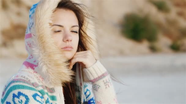 Mujer joven pensativa sentada en la playa, el viento soplando en su cara. Un día genial. tiempo para soñar — Vídeos de Stock
