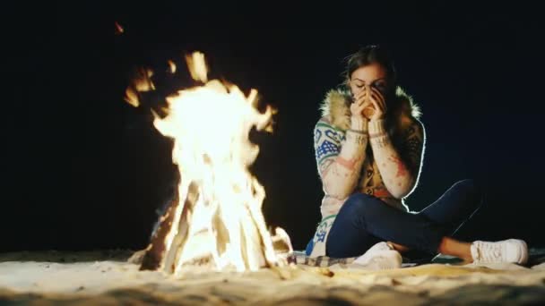 Mladá žena, sedícího u ohně, pití čaje, při pohledu na oheň