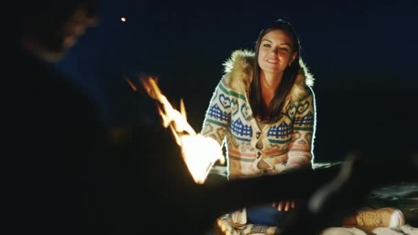 Amigos relajándose junto al fuego, un hombre en primer plano tocando la guitarra — Vídeos de Stock