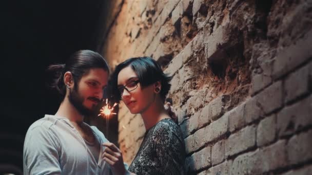 Jeune couple gothique hipster admire le scintillant. Debout sur un fond de mur de briques dans une maison abandonnée — Video