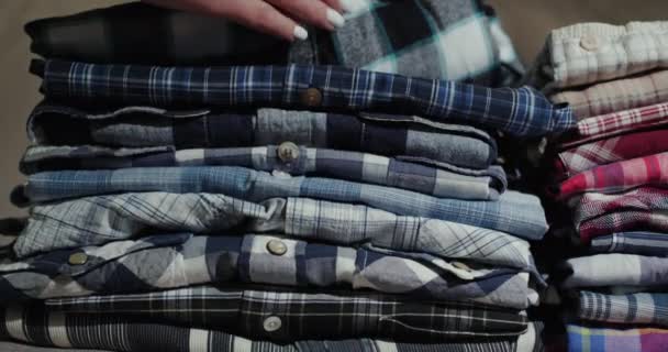 Женские руки сортируют по стопке мужских рубашек — стоковое видео