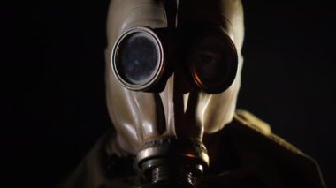 Yangının parıltıları adamın gözlerinde ve gaz maskesinde yansıyor.