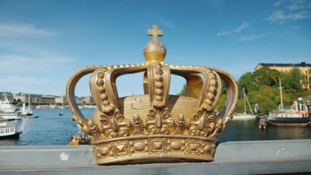 Royal Swedish crown on the Skeppsholmbron bridge over the river with harbor in the background. — Stock Video