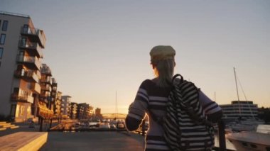 Aktif kadın marinada gün doğumunda seviniyor. Öne doğru koşuyor, ellerini kaldırıyor. Bergen 'de gün doğumu