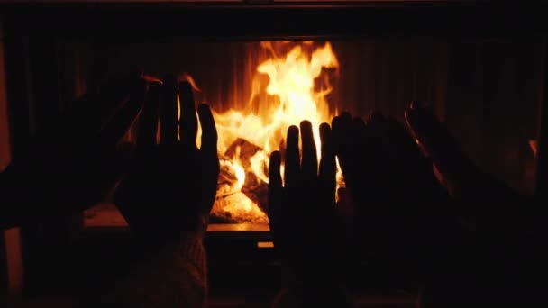 Mama, tata și copilul își încălzesc mâinile împreună lângă șemineu — Videoclip de stoc