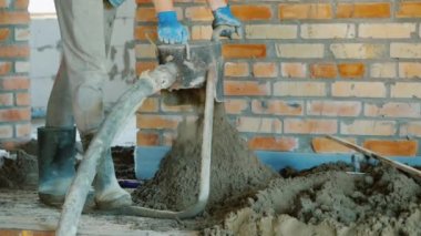 İnşaatçı zemini tamamlamak için yarı kuru havan topu koyuyor.