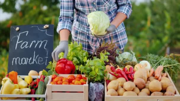 Продавец-фермер кладет капусту на стойку на овощном рынке — стоковое видео