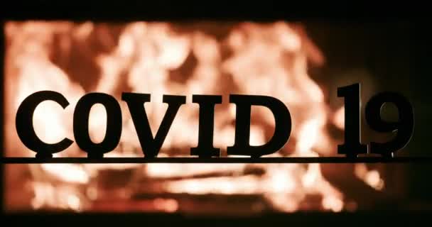 Тёмные буквы в слове Ковид-19 на фоне огня — стоковое видео