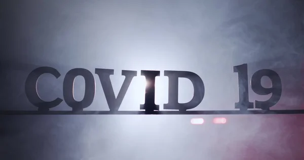 La palabra Covid-19 en la niebla con luces de ambulancia parpadeando detrás — Foto de Stock
