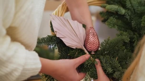 Жінки руками і дитиною роблять різдвяний вінок з хвойних — стокове відео