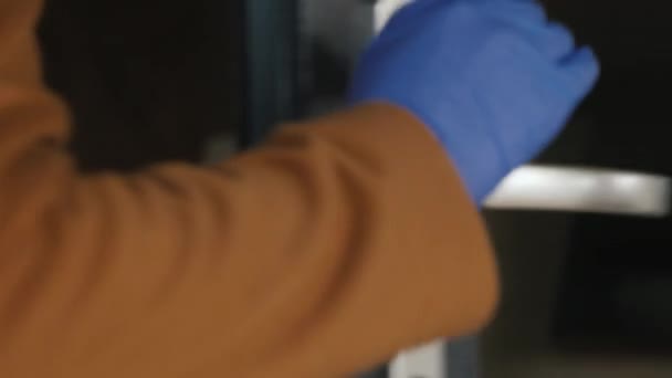 Ręka w rękawicy ochronnej otwiera drzwi za drzwiami. Ochrona przed koronawirem — Wideo stockowe