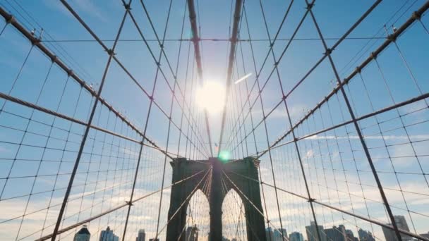 Прогулка по Бруклинскому мосту от Манхэттена до Бруклина. Солнце в зените светит в кадре — стоковое видео