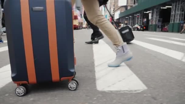 Vista lateral de Un turista con una bolsa sobre ruedas recorre las calles de Manhattan — Vídeos de Stock
