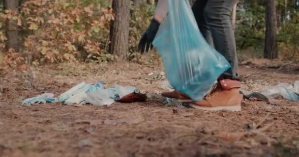 Une femme enlève les déchets des masques médicaux et du plastique dans la forêt — Video