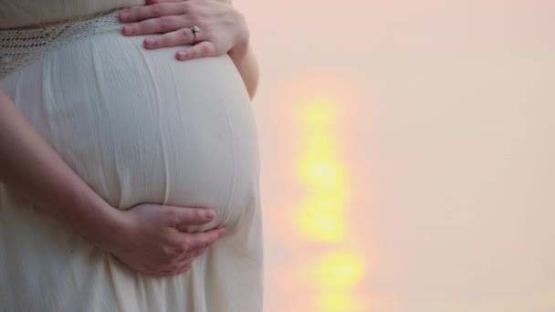 해 가지는 모습을 반영하는 바다를 배경으로 하는 임신 한 여자의 띠 — 비디오