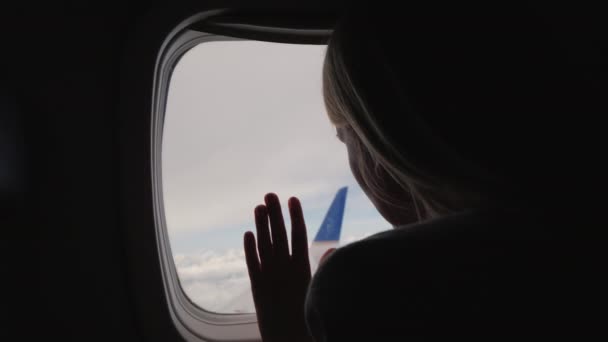 Silhouet van een vrouw die uit het raam van het vliegtuig kijkt. Achteraanzicht — Stockvideo