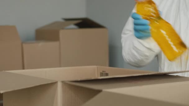 En person i skyddshandskar packar mat i en pappkartong — Stockvideo
