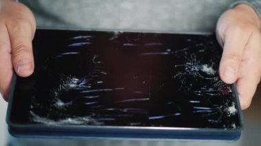 Bir adam kırık bir ekranla tablet tutuyor.