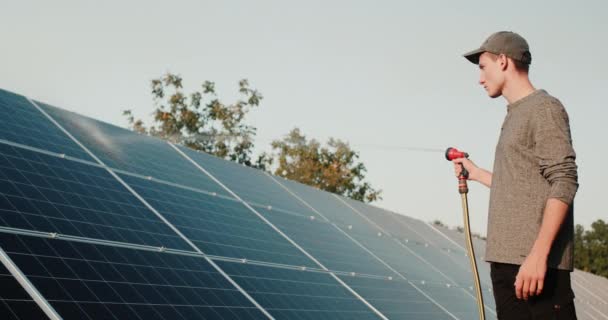 Joven se lava de los paneles solares de manguera — Vídeo de stock