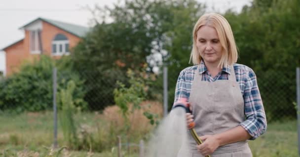 Een vrouw water geven planten in haar tuin — Stockvideo