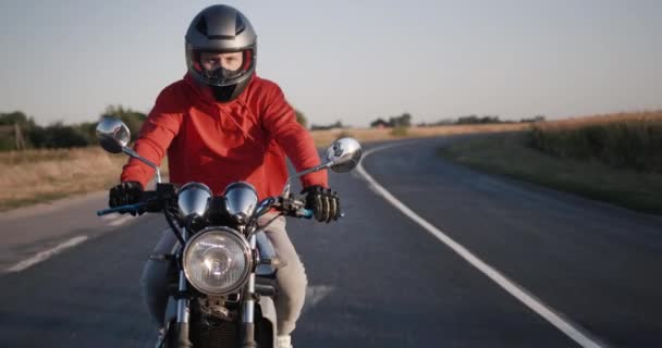 Genç bir adam motosiklet sürüyor, güneşli bir günde kırsal alanda keyifli bir yolculuk. — Stok video