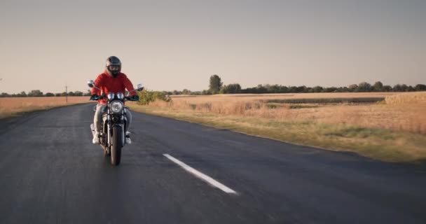 Jeune voyageur monte une moto le long des champs de maïs — Video