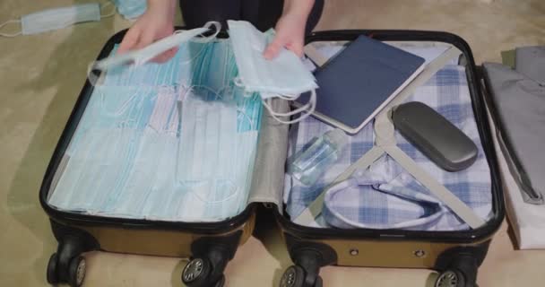 Kobieta wkłada wiele masek ochronnych do bagażu. Strach przed koronawirem — Wideo stockowe
