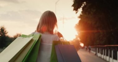 Paketleri olan bir müşteri gün batımında sokakta yürür.