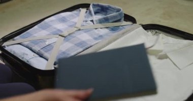 Gezgin giysilerini bir seyahat çantasına koyar, ayrıca koruyucu maskeler ve antiseptik de alır.