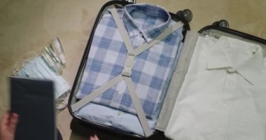 İş kadını giysilerini seyahat çantasına koyar, yanına maske ve antiseptik alır.