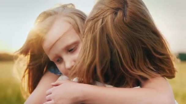 Mamma abbraccia sua figlia al tramonto, il vento gioca con i loro capelli — Video Stock