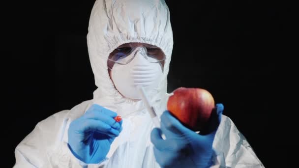 Un homme en vêtements et gants de protection prend un frottis d'une grosse pomme. Contrôle des plantes — Video