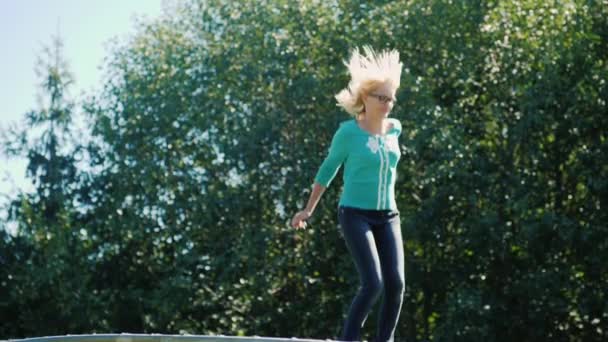 En kvinna hoppar högt på en studsmatta. Aktiv livsstil — Stockvideo