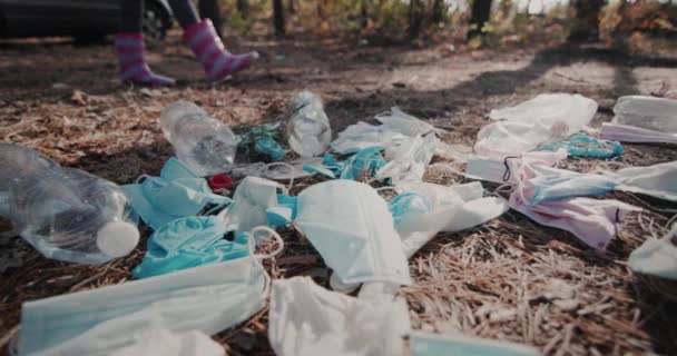 Mrazivé nohy v botách - procházejí lesem kolem hromady odpadků z lékařských masek. Koncept environmentálních otázek — Stock video