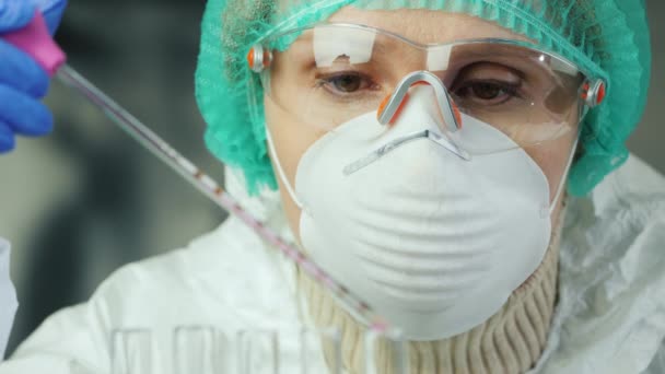 Seorang wanita dalam pakaian pelindung bekerja di laboratorium. Pengembangan narkoba baru — Stok Video