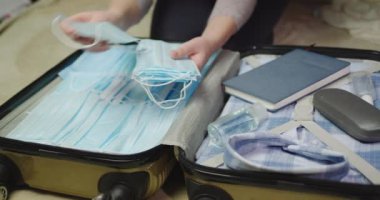 Kadın, Coronavirus 'a karşı korunmak için bagaja birçok maske koyar.