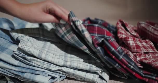 A női kezek egy halom férfi inget válogatnak. — Stock videók