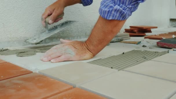 Bauarbeiter verlegt Keramikfliesen auf dem Boden auf der Veranda — Stockvideo