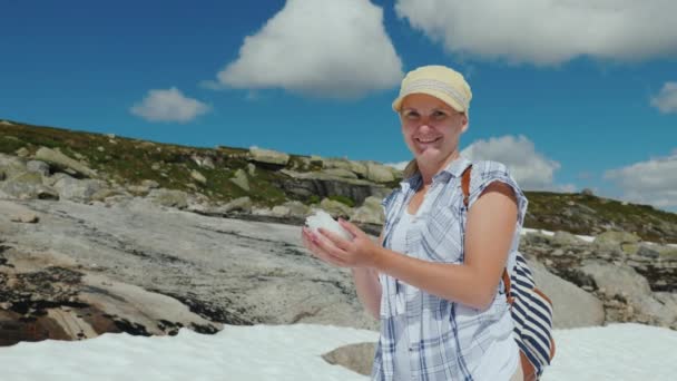 Gelukkige vrouw die sneeuwballen speelt op een gletsjer in Noorwegen. Warme zomer, maar de sneeuw is nog niet gesmolten - de geweldige natuur van Scandinavië — Stockvideo