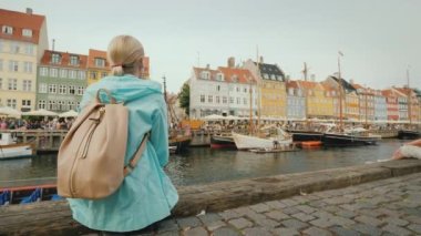 Kopenhag 'daki Nyhavn Kanalı' nın kıyısında dinlenen bir kadın.