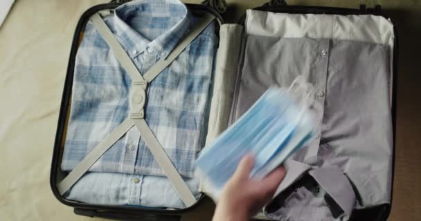 L'homme met des vêtements dans la valise, prend également des masques de protection et antiseptique — Video