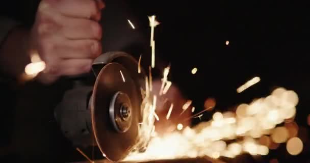 Mani di un lavoratore con un utensile elettrico, rettifica di metallo, scintille volare ai lati — Video Stock