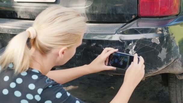 Een vrouw fotografeert een beschadigde auto bumper — Stockvideo