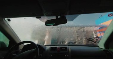 Şoför arabasını self-servis lavabosunda yıkıyor.