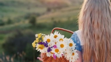 Arka plan: Bir çocuk elinde bir sepet çiçekle, yeşil tepelerin arka planında resim gibi bir yerde duruyor