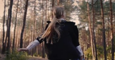 Ağır çekim video: Okul çantalı neşeli bir kız parkta koşuyor.