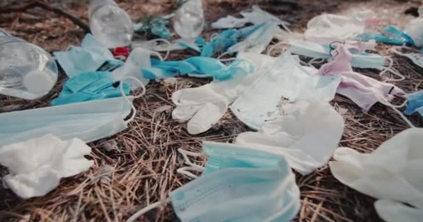 Beaucoup de masques médicaux usagés et d'autres débris reposent sur le sol dans la forêt — Video