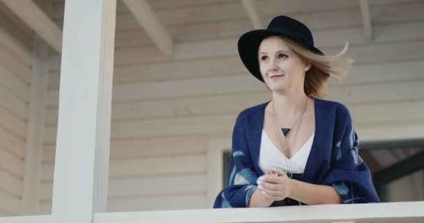 Snygg kvinna i hatt på terrassen i sitt hem — Stockvideo